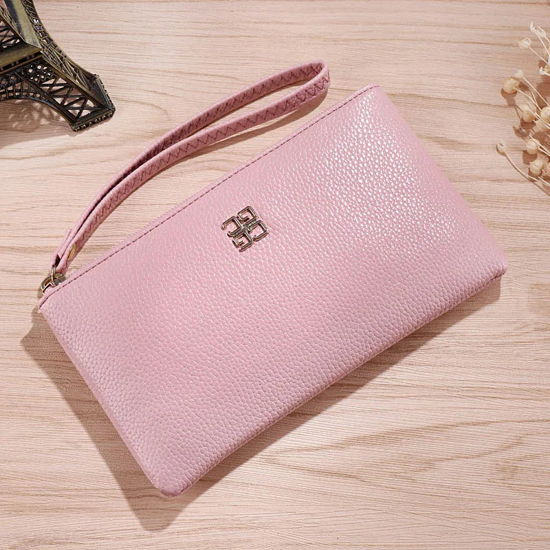 A light pink Litchi-Grain PU leather long wallet with a strap resting on a wooden surface.