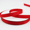 Red satin ribbon rolls coiled and overlapping on a white background.