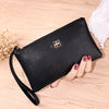 A black Litchi-Grain PU leather long wallet with a strap is shown resting on a wooden surface.