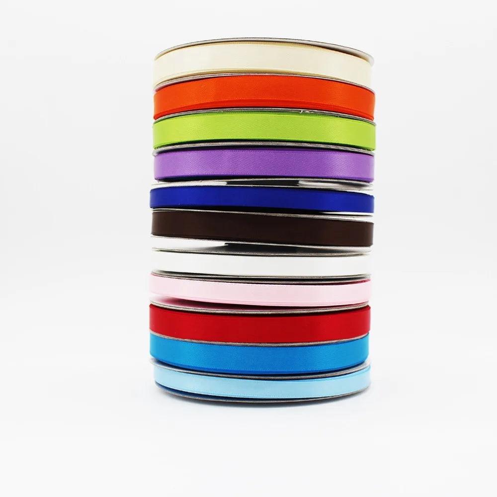 A stack of double-faced satin ribbon rolls in a rainbow color spectrum.