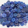 A pile of assorted purple and blue wooden buttons for sewing and crafts.