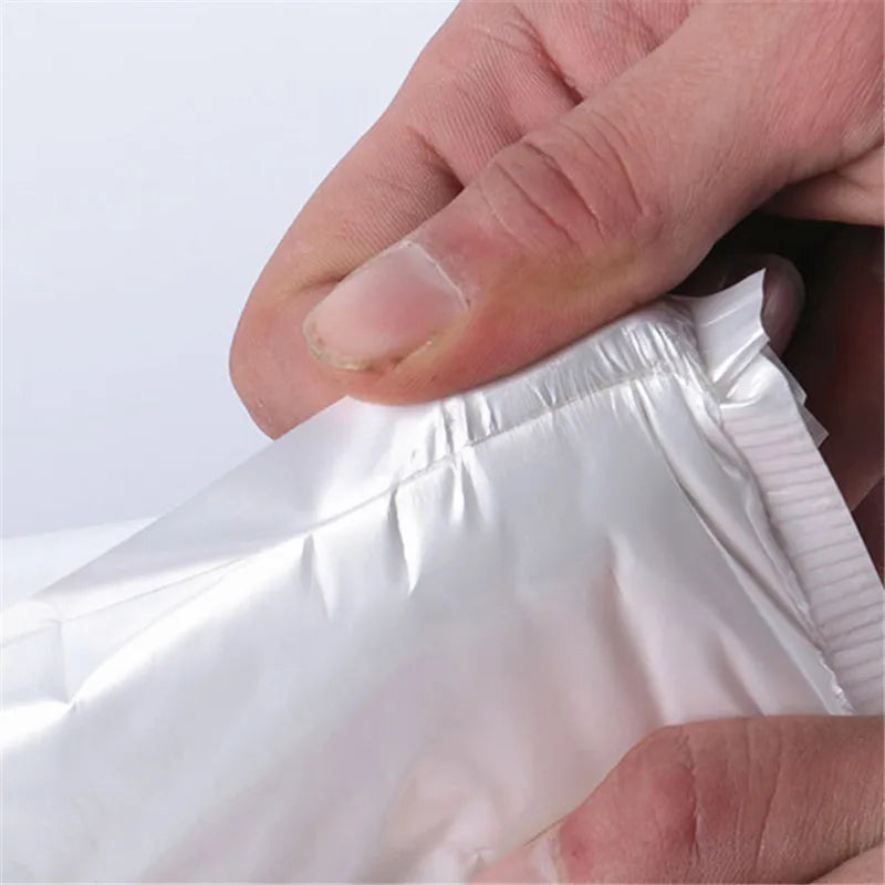 A hand is holding a white waterproof foam paper envelope.