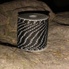 A roll of black and white high-visibility reflective paracord resting on a dark rock.