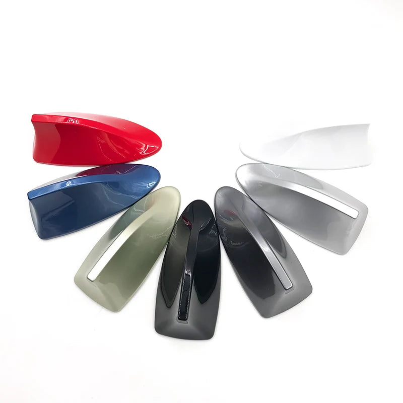 A collection of various colored car shark fin antenna covers, including red, blue, silver, and black.