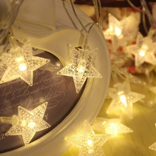 A close-up of a white light-up star decoration hanging, with other similar stars blurred in the background.