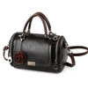 A black leather crossbody shoulder bag with brown leather handles and a rose pendant.