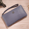A gray Litchi-Grain PU leather long wallet with a strap is shown on a wooden surface.