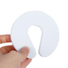 A white foam door stopper with a finger pinch protection design being held by a hand.