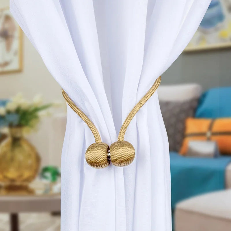 Gold magnetic pearl ball curtain tiebacks on a white fabric drape