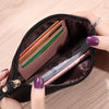 A hand is holding an open dark brown wallet with a phone pocket, showing several cards and a smartphone inside.
