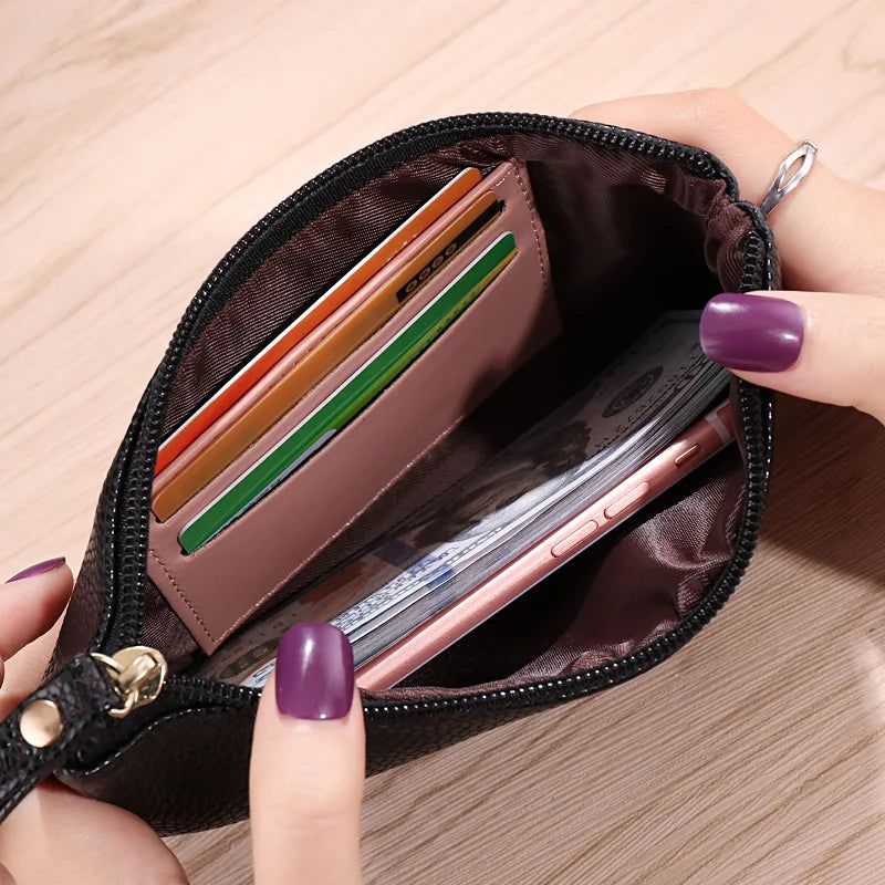 A hand is holding an open dark brown wallet with a phone pocket, showing several cards and a smartphone inside.