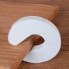 A white foam door stopper with a curved shape is shown resting on a wooden surface.