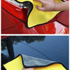 A hand is using a yellow microfiber car care towel to wipe a red car's exterior.