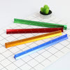 A collection of colorful aluminium triangular scale rulers laid on a white grid paper next to a small green cactus.