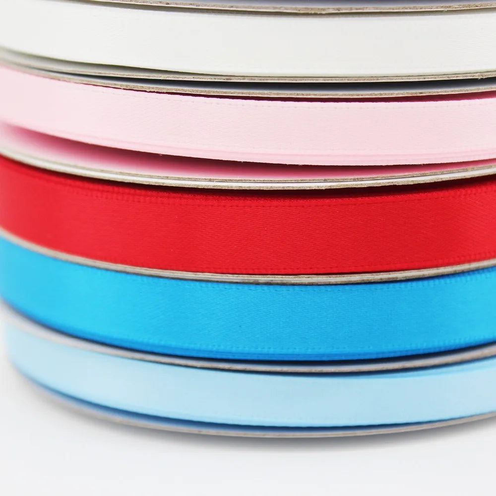 A stack of double-faced satin ribbon rolls in various colors including pink, red, and blue.