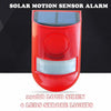 A red solar motion sensor alarm device with a lens and a visible solar panel on top.