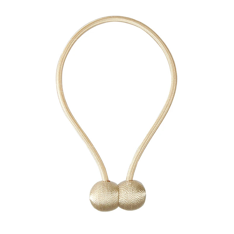 A delicate gold-colored cord with two small ball knots used as a curtain tieback.