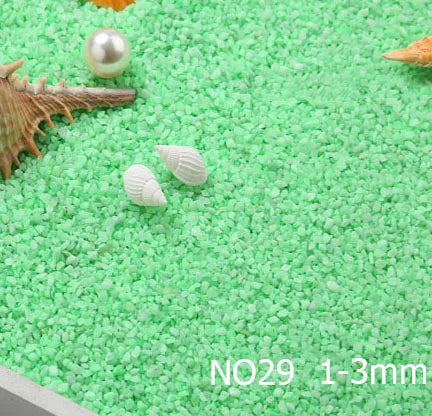 Green decorative stone pebbles with seashells and a pearl on a white surface