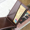 A brown leather wallet with a magnetic closure and an ID card visible inside, resting on a wooden surface.