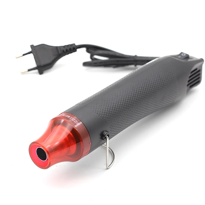 A black electric heat gun with a red tip and a cord is shown against a white background.