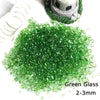 A pile of green glass pebbles measuring 2-3mm next to a small decorative stone figure.