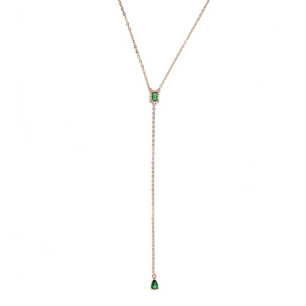 A delicate rose gold lariat necklace featuring a geometric teardrop pendant with a green cubic zirconia stone.