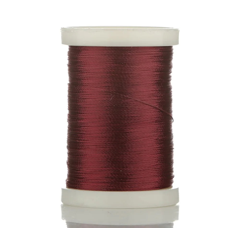 A spool of deep reddish-maroon braided polyester thread for guide tying and repairs.
