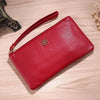 A red Litchi-Grain PU leather long wallet with a phone pocket resting on a light wooden surface.
