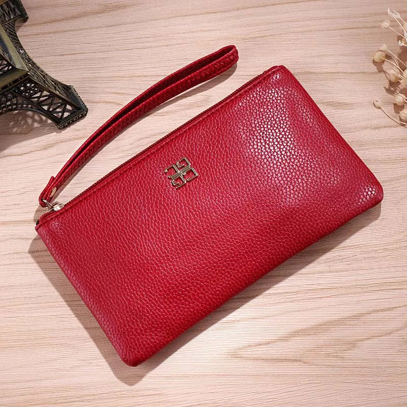 A red Litchi-Grain PU leather long wallet with a phone pocket resting on a light wooden surface.