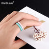 A hand wearing a turquoise braided silicone ring on its finger, resting on a white card.