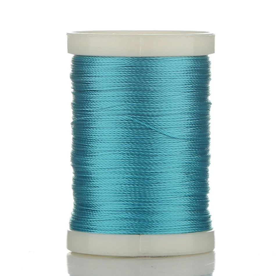 A spool of teal blue braided polyester thread for guide tying and repairs.