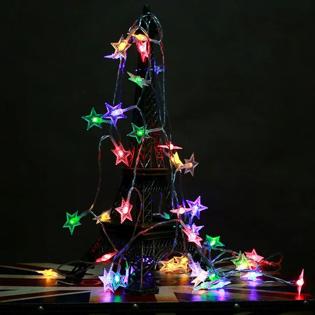 A lighted Christmas tree shaped like a tipi, decorated with colorful star lights.