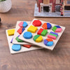 A wooden geometric shape sorting puzzle with colorful blocks laid out on a wooden table.