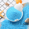 Bright blue decorative stone pebbles and seashells scattered on a white surface.