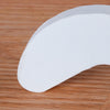 A white foam door stopper with a curved shape is shown resting on a wooden surface.