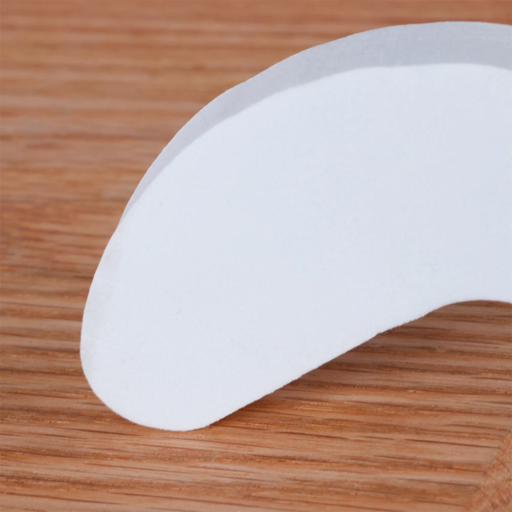 A white foam door stopper with a curved shape is shown resting on a wooden surface.