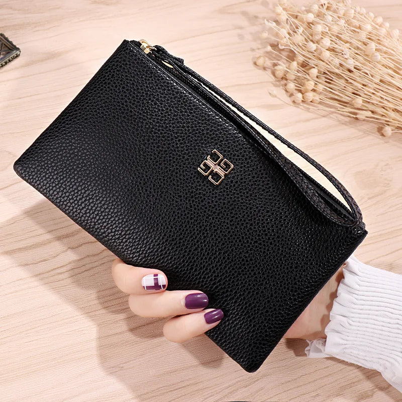 A black Litchi-Grain PU leather long wallet with a gold logo is shown being held on a wooden surface.