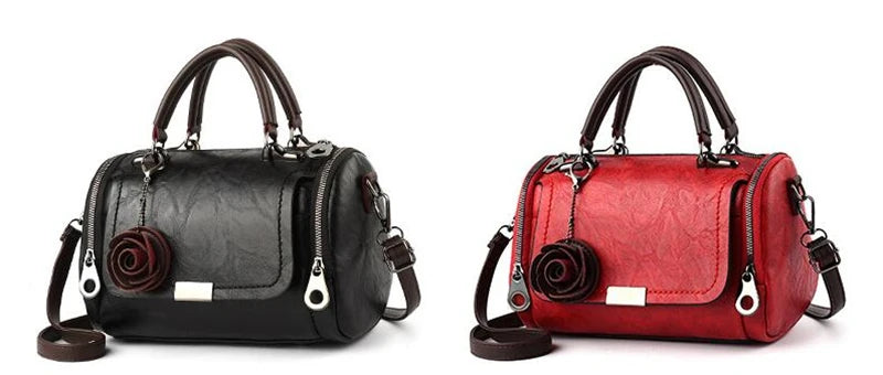 A black leather handbag with a floral pendant and a red leather version of the same bag.