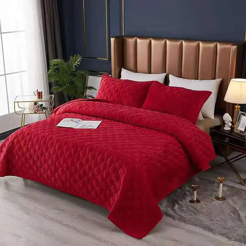 A luxurious red quilted velvet bedspread with a non-slip design displayed on a bed.