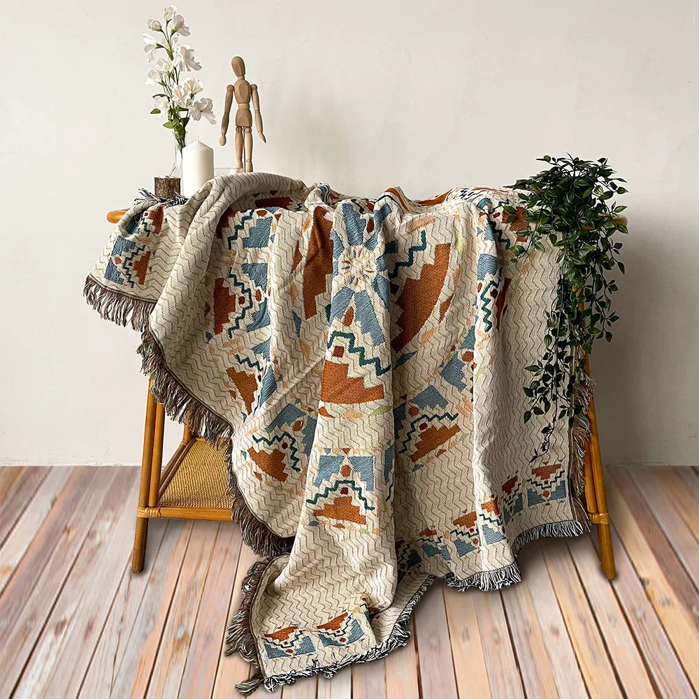 A beige and rust colored bohemian jacquard woven throw blanket draped over a wooden chair.