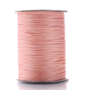 A spool of pink waxed cotton cord used for jewelry making