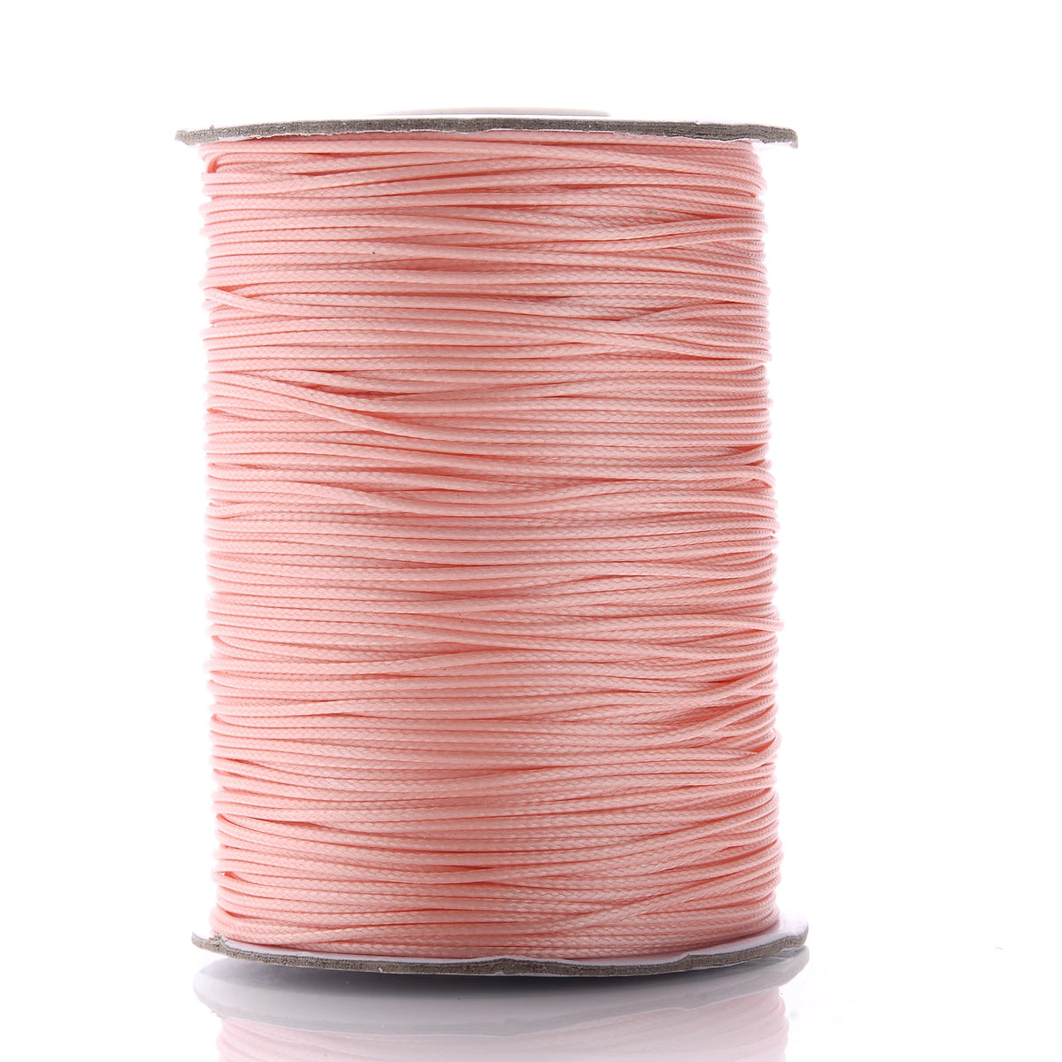 A spool of pink waxed cotton cord used for jewelry making