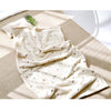 A cream-colored coral fleece baby blanket with subtle bear embroidery is draped on a light beige surface.