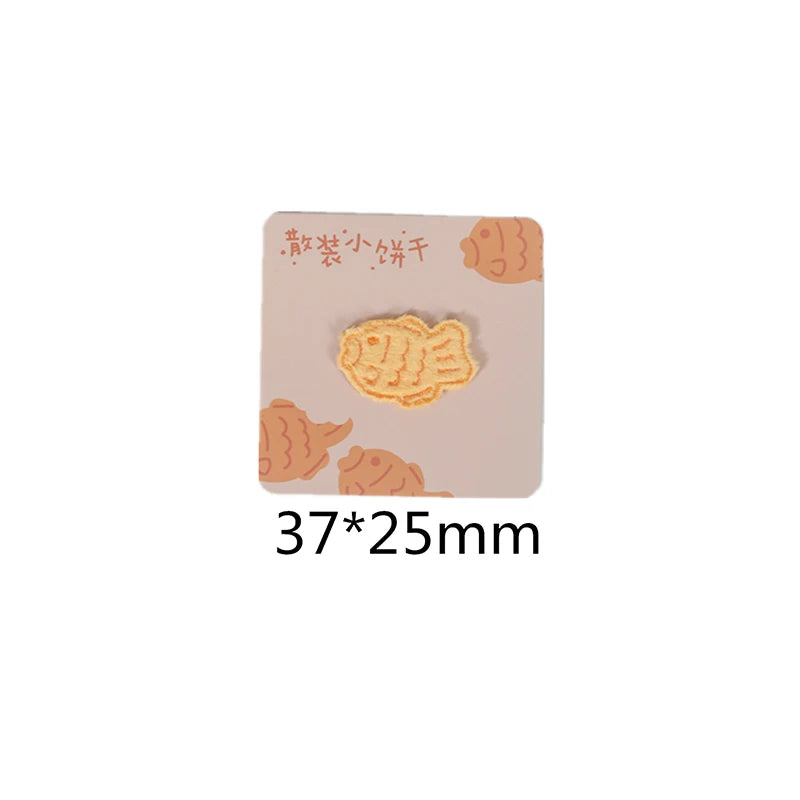 A square beige iron-on patch featuring an embroidered illustration of a fish.