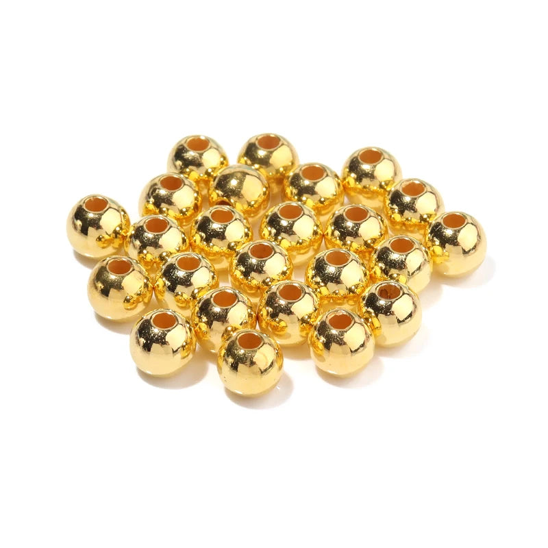 A pile of round gold-colored imitation pearl beads for jewelry making.