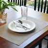 A set of six linen hemstitch napkins is displayed on a wooden table with glassware and silverware.