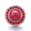 Silver snap button with a central red gemstone surrounded by smaller red stones.
