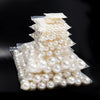 A pile of round white ABS imitation pearl beads for jewelry making displayed on a dark background.
