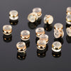 A collection of silicone rubber ear back stoppers with copper rings arranged on a dark reflective surface.