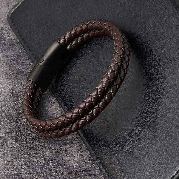 Pulsera de cuero marrón oscuro trenzado con cierre magnético sobre una superficie de gamuza gris oscuro.